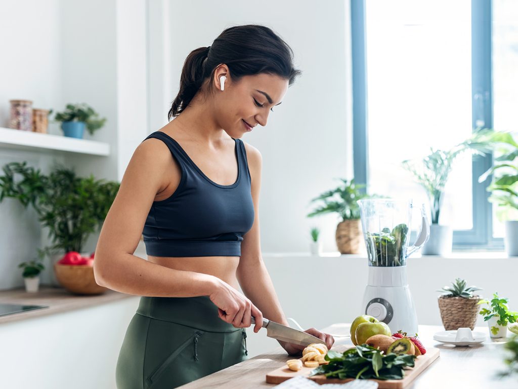 Woman in gym gear chopping fruit