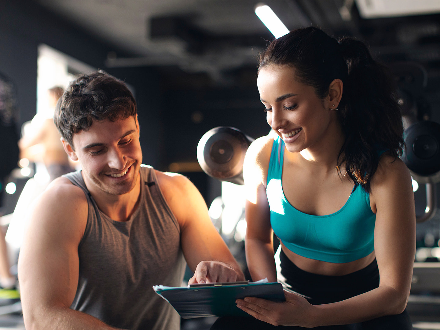 Man in gym giving female instructor feedback on iPad