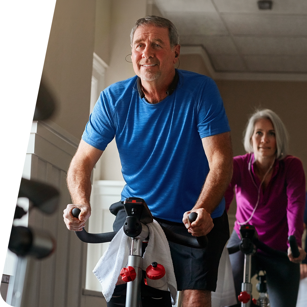 Older man and woman riding an exercise bike