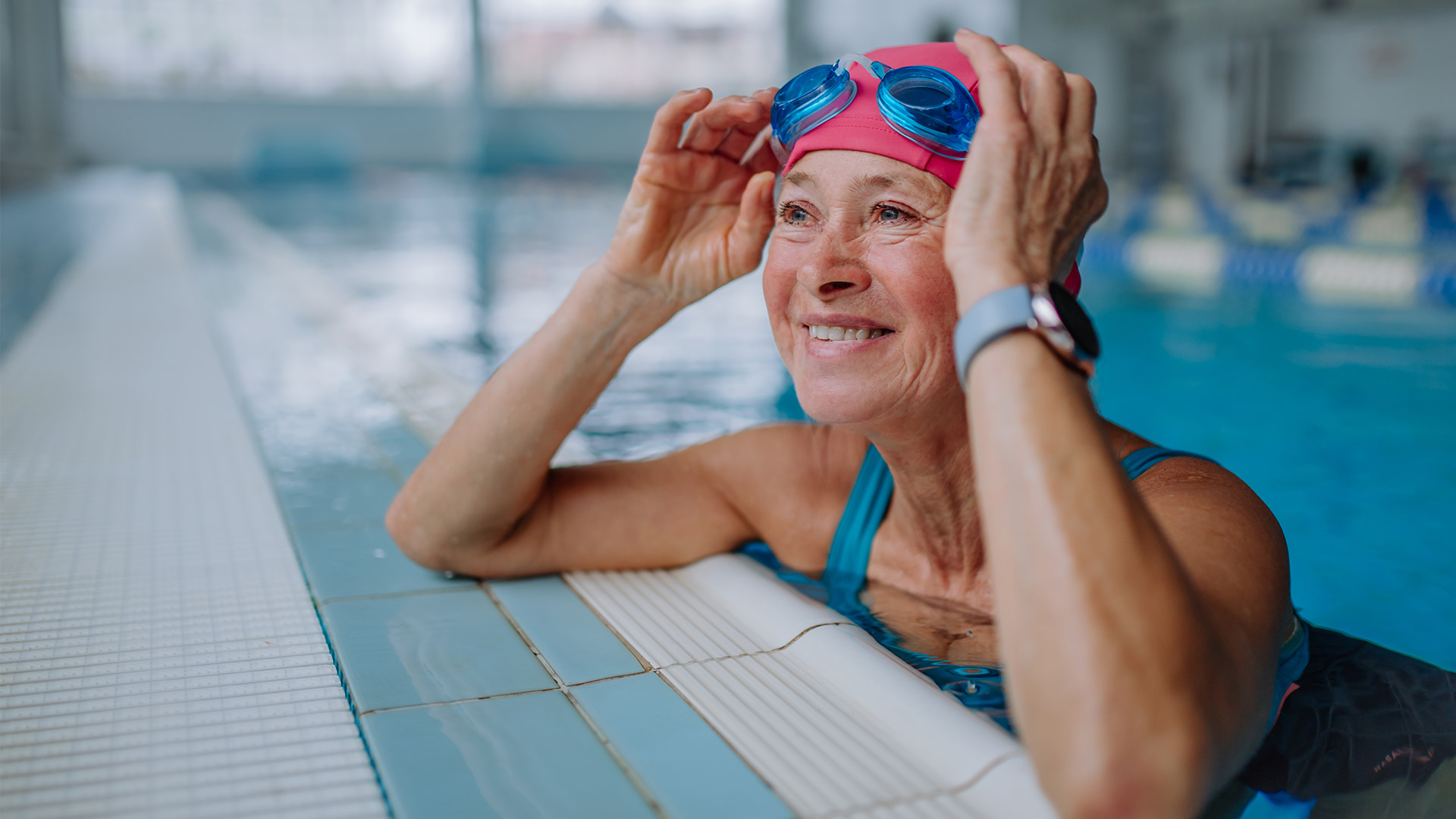 Older woman adjusting googles in swimming pool